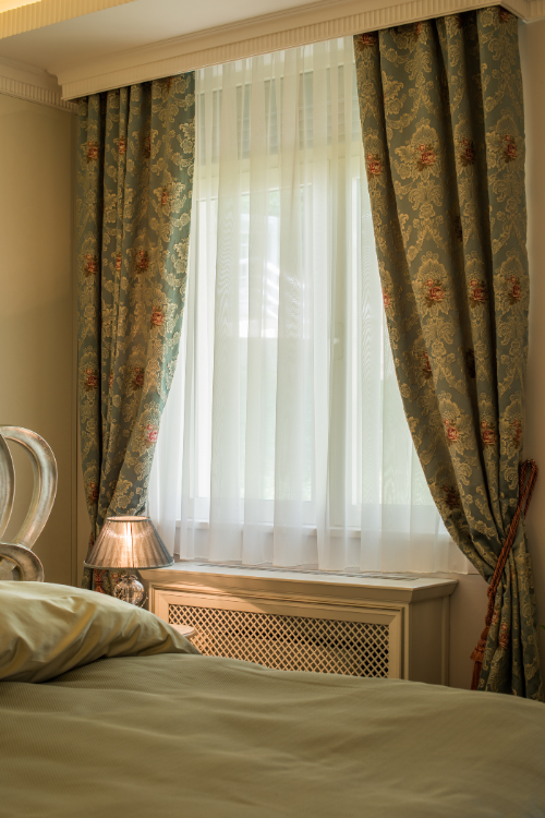 A close-up of a luxurious bedroom window with floral curtains and sheer drapes, a perfect touch for elegant home furnishing.
