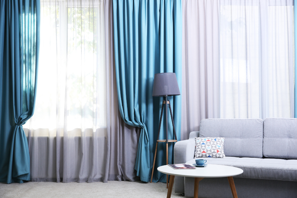 A modern living room with stylish blue and gray layered curtains, perfectly designed by a Home Decor Company in India.